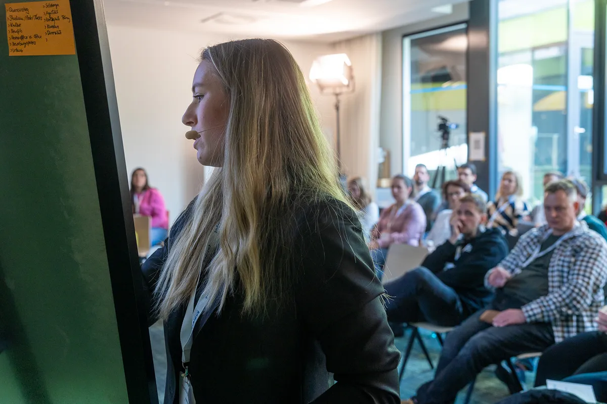 Speakerin mit Headset präsentiert vor Publikum in einer Session bei einer früheren T4AT-Ausgabe